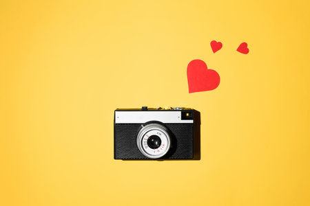 Vintage photo camera and red hearts on a yellow background. flat lay. Like photo conceptの写真素材