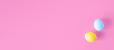 easter banner. Two multi-colored eggs lying on a pink background, flat lay. Festive background, copy space. happy easter conceptの写真素材