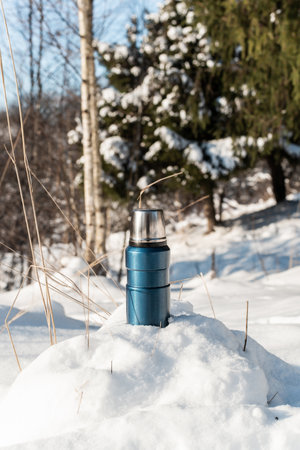 flask standing on a snowy hill, close-up. vertical photo. winter forest sunny day backgroundの写真素材