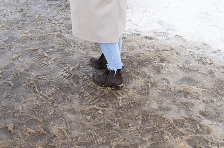 A woman standing in the melted snow, cropped. Thaw, slush, dampnessの写真素材