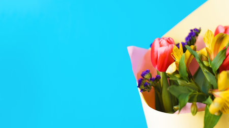Beautiful bouquet of flowers on a blue background, close-up. Decorated lilies and tulips, copy space.の写真素材
