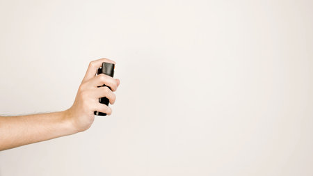 Male hand holding pepper spray on a light background, copy space. Self-defense concept.の写真素材