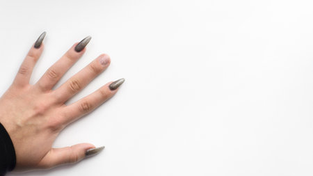 Female hand with a broken nail on a white background, top view. Banner, copy space. Damaged gel polish. Bad manicureの写真素材