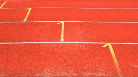 Side view of red running tracks in a street stadium. White and yellow rubberized treadmill markings.の写真素材