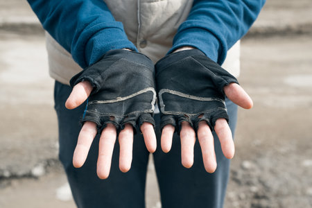 Man showing hands in torn sports gloves from training. Used sportswear, close-up.の写真素材