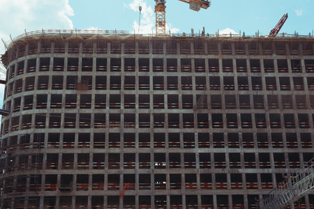 Construction and architecture. Exterior view of high-rise apartment building under construction in city on sunny day outdoorsの写真素材