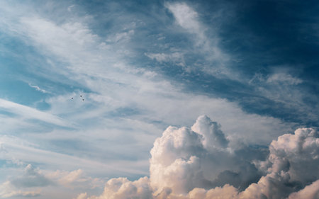 Beautiful fluffy clouds and small birds against the blue sky, heavenly windy landscape. Natural backdrop.の写真素材