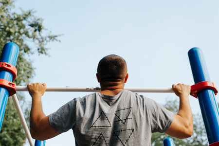 Athletic strong man exercising on horizontal bar, back view. Workout, gymnastics, strength training...