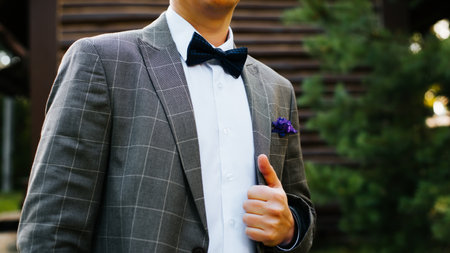 Man in suit, plaid jacket, white shirt and with bow tie outdoors, cropped image. Selective focus on blue groom's bow tie.の写真素材