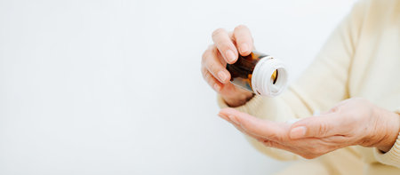 Seniors and healthcare, pharmaceutical treatment banner with copy space. Senior sick woman holds bottle of medicine capsules in her hand, takes antibiotics, pain relievers pills, close-up.の写真素材