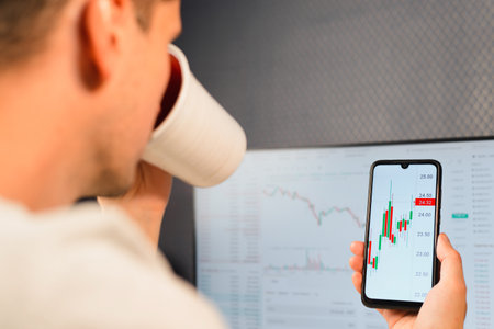 Close-up trader investor broker analyzing stock market, crypto, growth chart, profit and loss in mobile app at workplace. Business and finance, investment and technology. Selective focus on smartphoneの写真素材