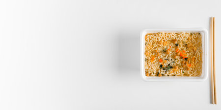 Chinese instant noodles in plastic box with wooden chopsticks on white table, banner with copy space...
