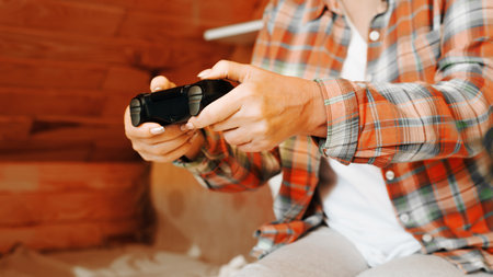Side view of woman in casual clothes playing video game using wireless joystick. Close-up of female...