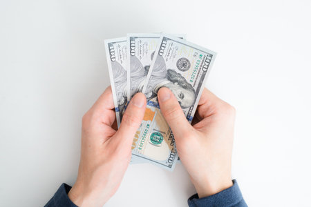 Top view hands counting money. Human caucasian hands holding one hundred dollar bills, cash on white...
