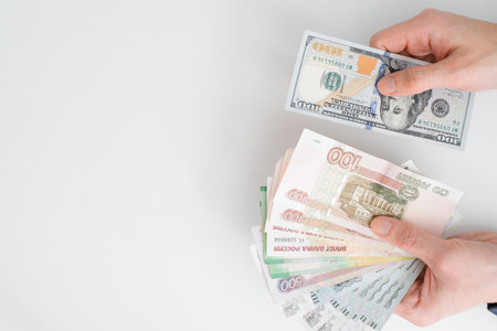 Top view human hands holding rubles and one hundred dollars, close-up. Financial crisis, economic...