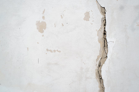 Damaged wall with crack, copy space. Textured uneven background of rough concrete wall.