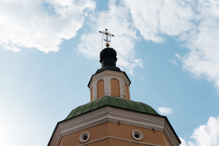 Close-up of church with cross against cloudy blue sky on sunny day, exterior.の写真素材