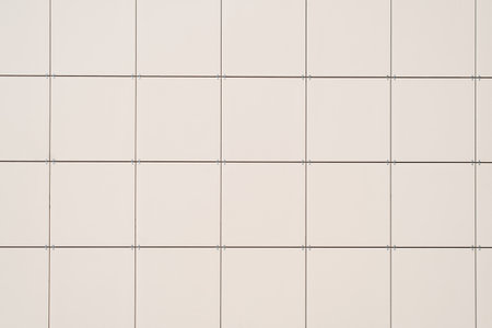 Tiled wall of large light ceramic tiles outdoors. Building facade close-up.