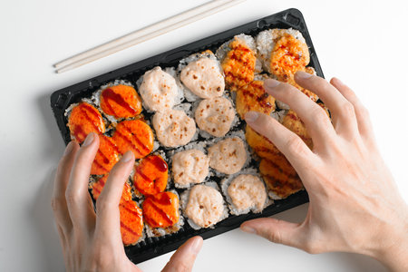 Close-up of hungry hands reaching for hot baked yaki maki rolls. Japanese traditional sea food cuisine. Close-up, top view.の写真素材