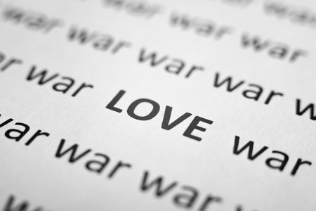 War and peace, picifist concept. Close-up of printed text of words War and one word Love on white paper. Low angle view, selective focus, macro photo.の写真素材