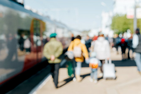 Defocused crowd of people of passengers and modern high-speed train on platform of railway station on sunny day outdoors. Journey, trip, tourism concept.の写真素材