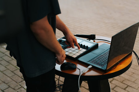 Street musician beatmaker plays hip-hop on midi controller drum machine in an open air. Close-up,...