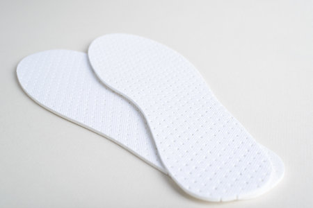 White hygienic insoles for shoes on light background. Close-up, low angle view, selective soft...