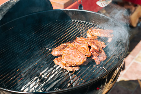 Close-up of sirloin steaks being grilled outdoors.