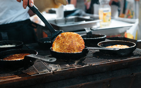 Close-up of chef cooking potato pancakes at street food festival. Pan fried draniki, hash brown.の写真素材