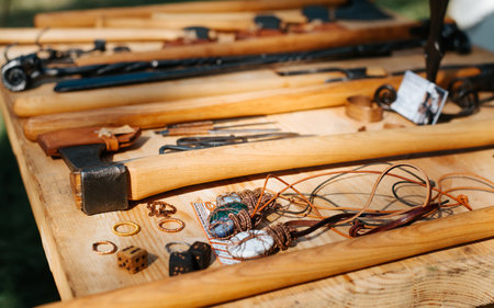 Medieval axes and handmade metal jewelry sold at the market fair. Close-up, selective focus.