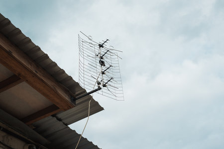 Passive antenna for receiving radio and TV signals mounted on roof of building against sky.の写真素材