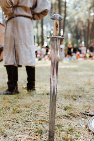 Medieval old steel sword stuck in the ground. Close-up, selective focus on the blade of the weapon.の写真素材