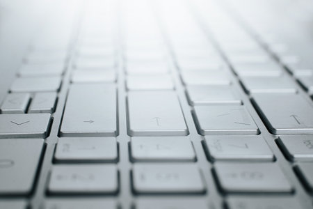 Close-up gray laptop keyboard. Low angle view of computer key, selective soft focus, perspective.