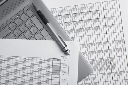 Top view bills, documents, pen lying on laptop at workplace close-up. Balance, budget, business and...