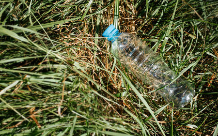 Used plastic bottle on green grass, copy space, top view. Garbage in nature, environment pollution concept.の写真素材