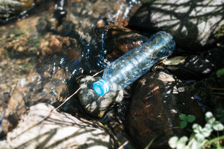 Environmental pollution with plastic concept. Plastic bottle in the water, garbage in the creek...