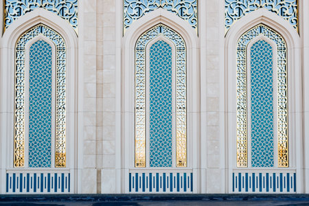 Beautifully decorated stained glass windows with blue glass in stone arches, oriental architecture. Exterior of a religious Islamic building, front view.の写真素材