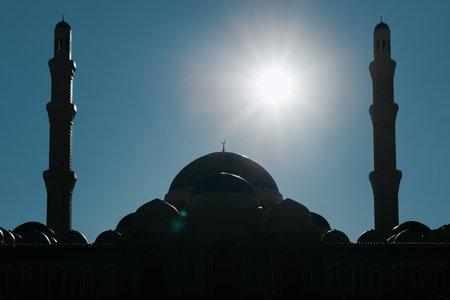 Silhouette of the mosque against the blue sky on a sunny day. Ancient arabic religious building, dome and high minarets, muslim faith and religion.の写真素材