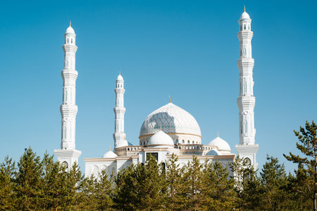 Part of white large beautiful mosque with minaret, outdoors. Oriental religious architecture, Muslim prayer building against a clear sky, exterior.の写真素材