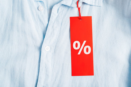 Sale, discount, black friday concept. Red tag with discount symbol Percent hanging on a light shirt,...
