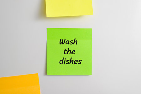 Self-adhesive sticker with reminder message Wash the dishes stuck on refrigerator in kitchen,...