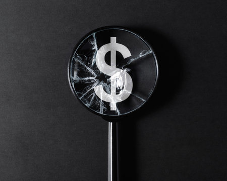 Inflation, economic crisis, financial problems, recession concept. Close-up of broken cracked magnifier glass focused on dollar sign on black background.の写真素材