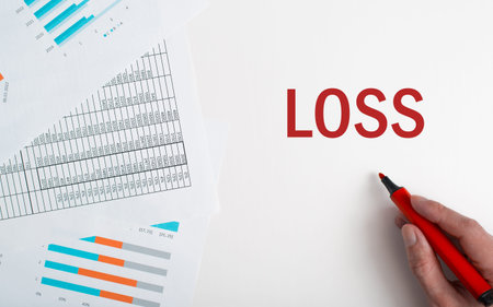 Falling profit, economic loss, recession business concept. Close-up of hand writing with red marker word Loss, financial documents on table.