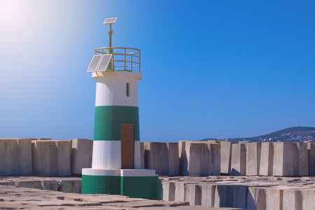 Green stripped light house surrounded by sea breakersの写真素材