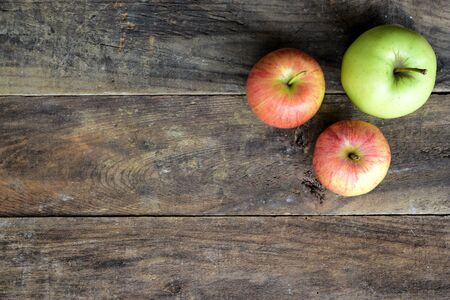 Vertical view of two red and on green apples on top of an old wood tableの写真素材