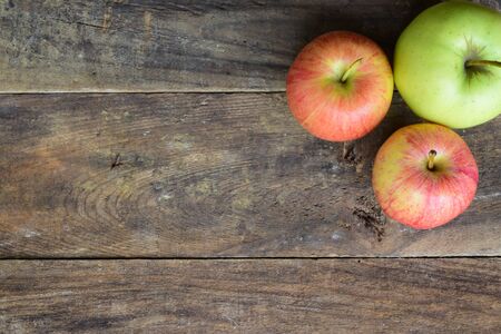 Vertical view of two red and on green apples on top of an old wood tableの写真素材