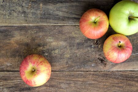 Top view of three red apples and one green apple on a old wood tableの写真素材