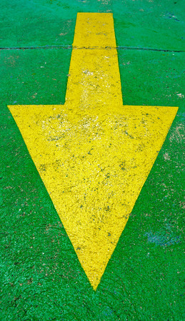 Big yellow arrow on the green background pointing downの写真素材