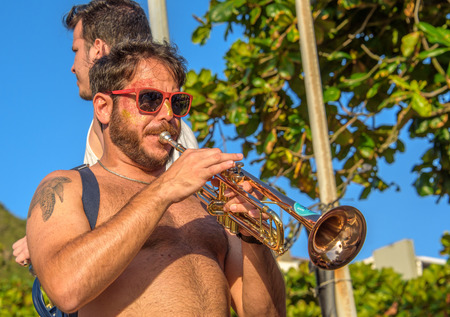27 November, 2016. Man in sunglasses with tattoo of turtle playing trumpet in the street at sunny day at Festival de Fanfarras Ativistas - HONK RiO 2016 at Leme district, Rio de Janeiro, Brazilのeditorial素材