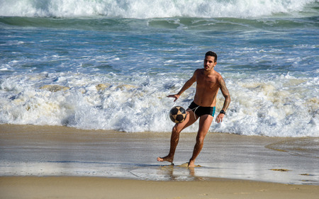 6 December 2016. Man playing beach football in motion, kicking the ball on the background of waves of Atlantic ocean at Copacabana beach, Rio de Janeiro, Brazilのeditorial素材